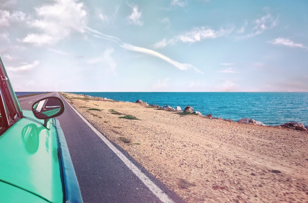 Green car driving near the ocean in the summer